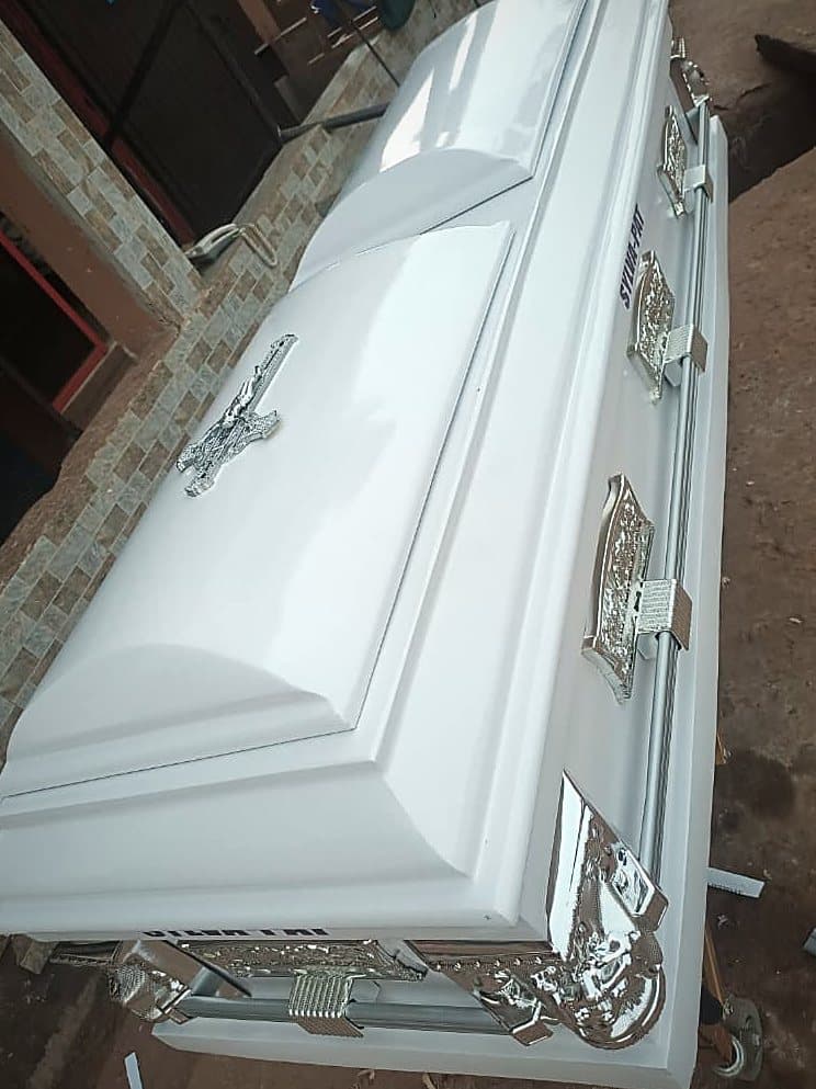 A white dome-lid casket with a chrome bar handle and chased silver corner mounts