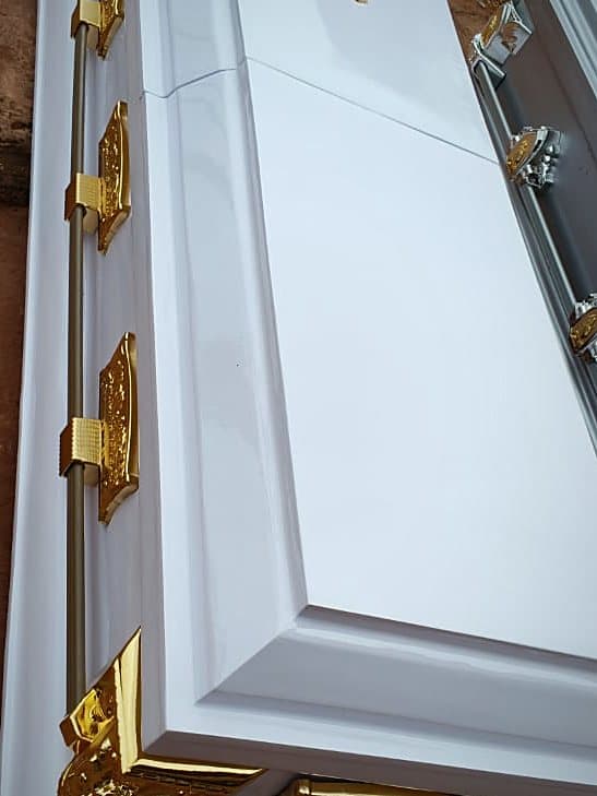 A white dome-lid casket with gilt corner mounts and a gilt crucifix on the lid