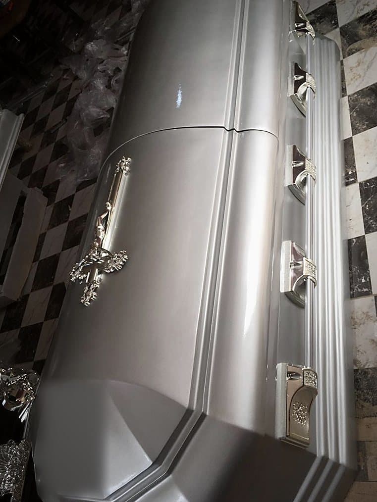 A matt silver graduation-shape casket, the stepped profile picked out in shadow