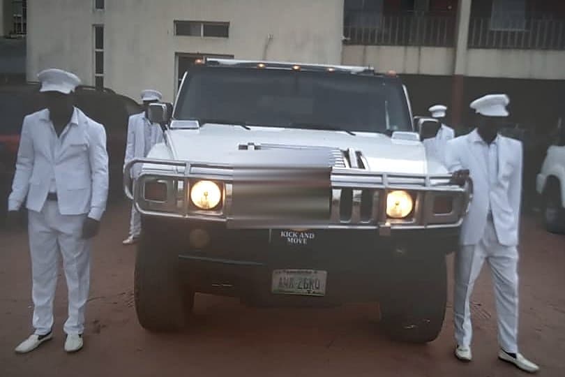 The Hummer with two attendants in white standing either side, lamps lit