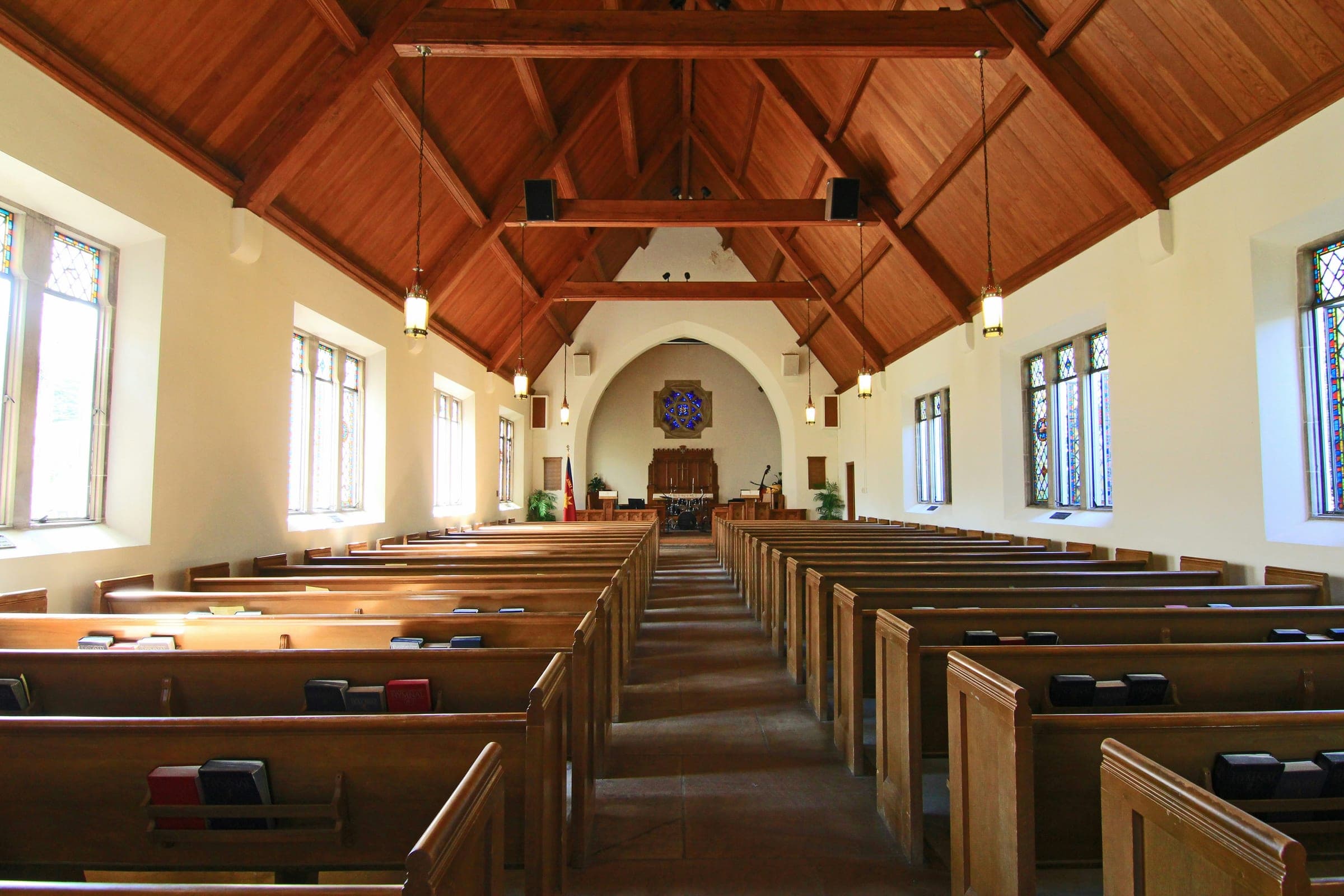 Daylight falling through the windows of an empty church, pews on either side of the aisle