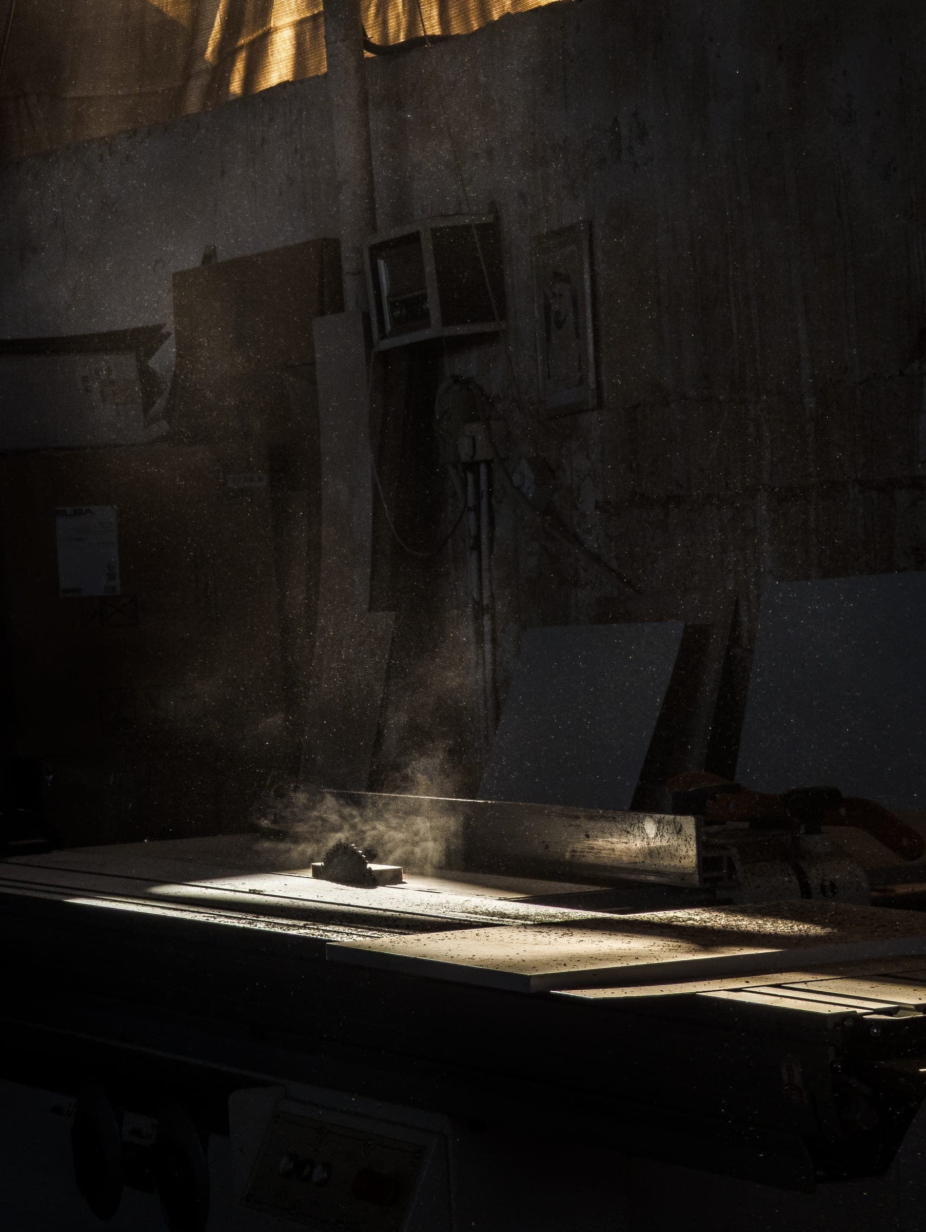 A workshop bench in low light, sawdust hanging in a shaft of sunlight